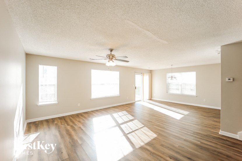 A spacious room with wooden floors and a ceiling fan.