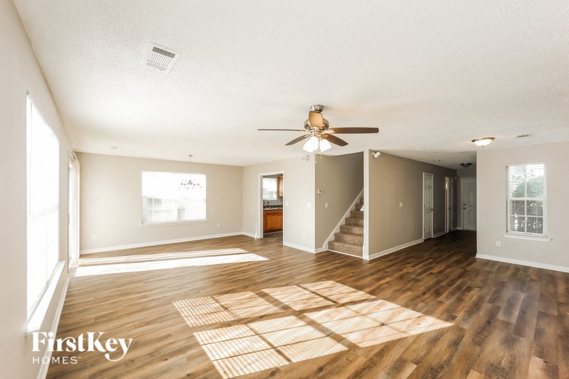 A spacious room with wooden floors and a ceiling fan.