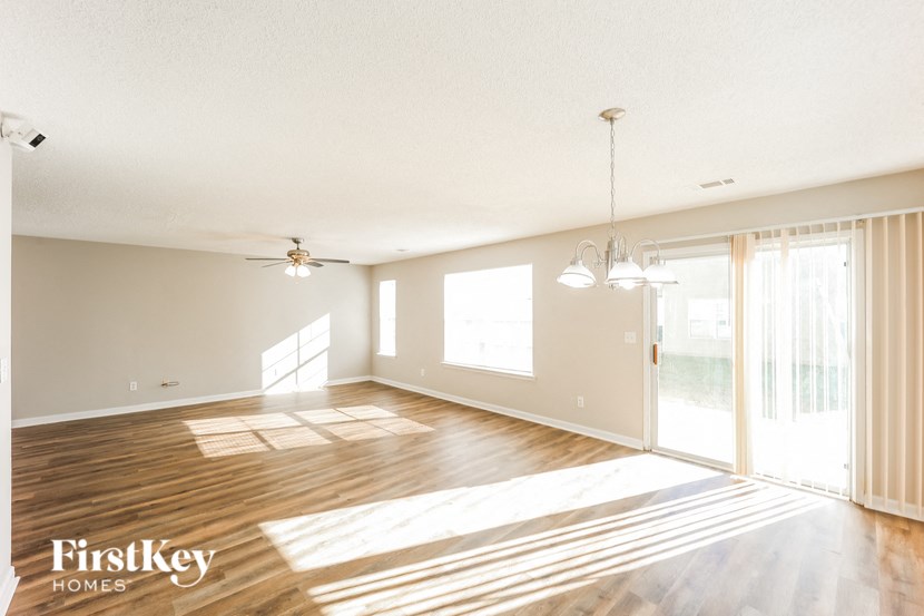 A spacious room with wooden floors and a ceiling fan.
