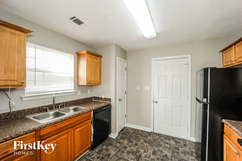 A kitchen with a black fridge and wooden cabinets.