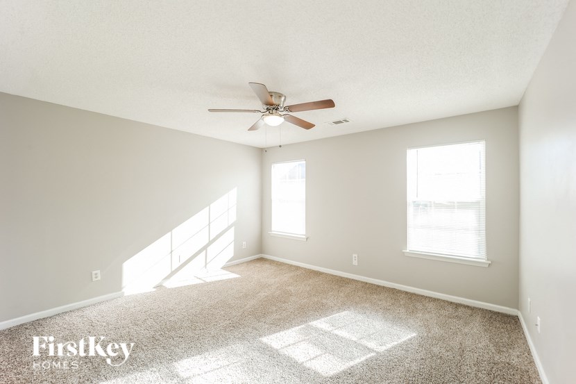 A spacious room with a carpeted floor and a ceiling fan.