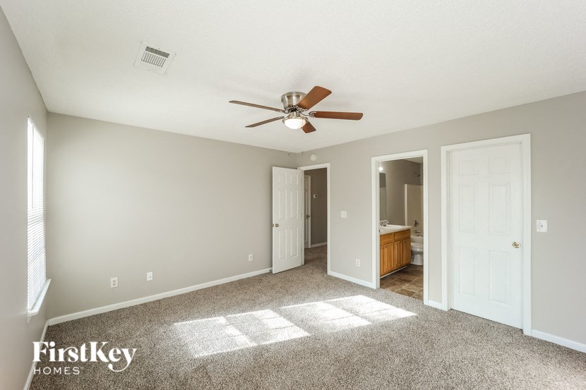 A spacious room with a ceiling fan and a carpeted floor.