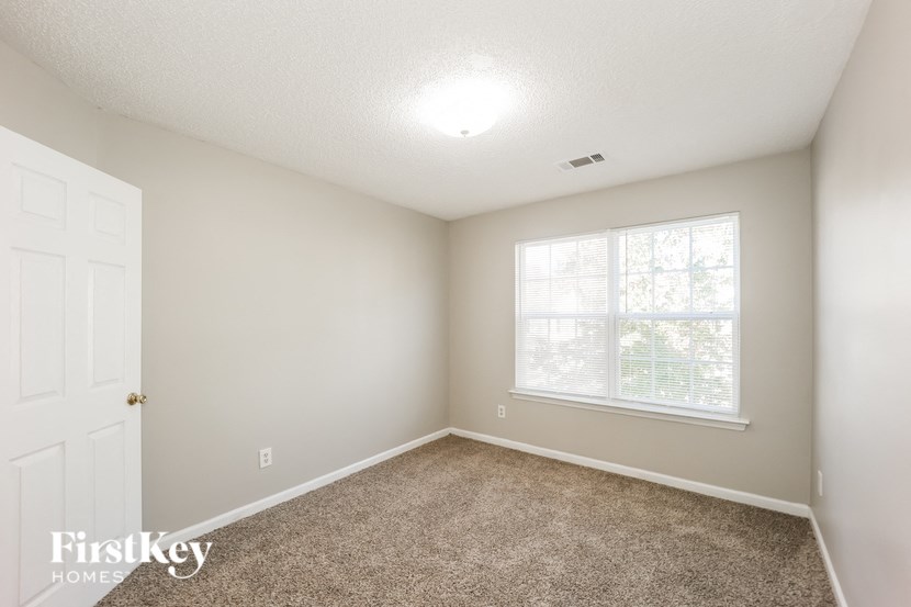 A room with a carpeted floor and a window letting in light.