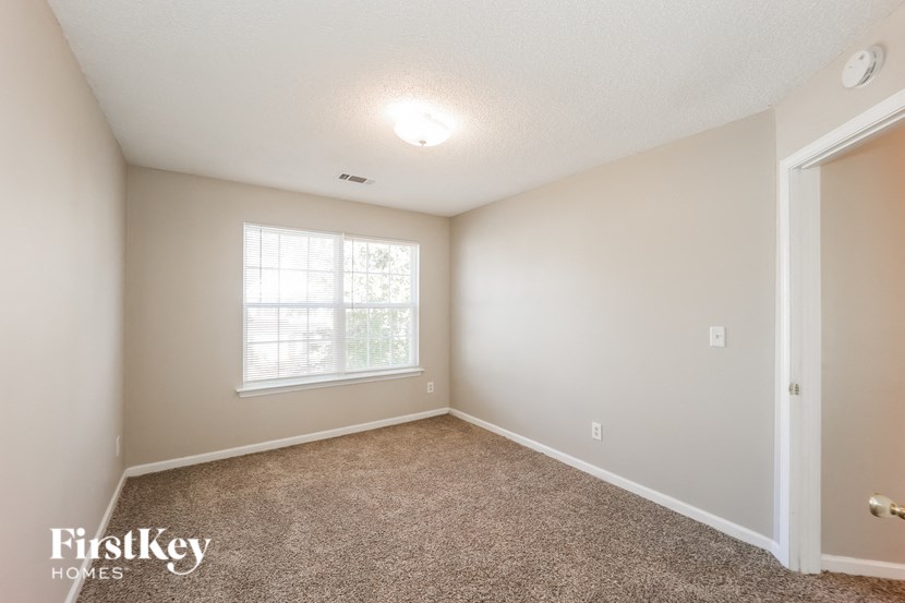 A room with a carpeted floor and a window letting in natural light.