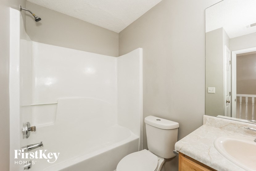 A white bathroom with a toilet, sink, and bathtub.