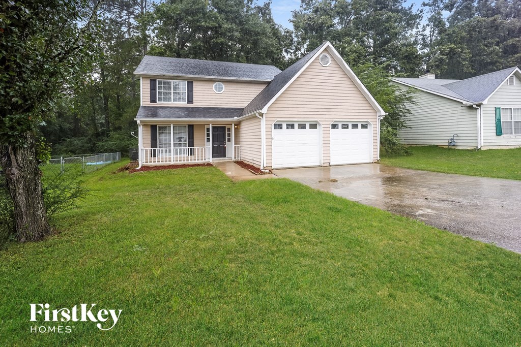 a white house with a yard and a rain soaked driveway