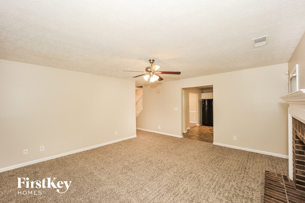 a spacious living room with carpet and a ceiling fan