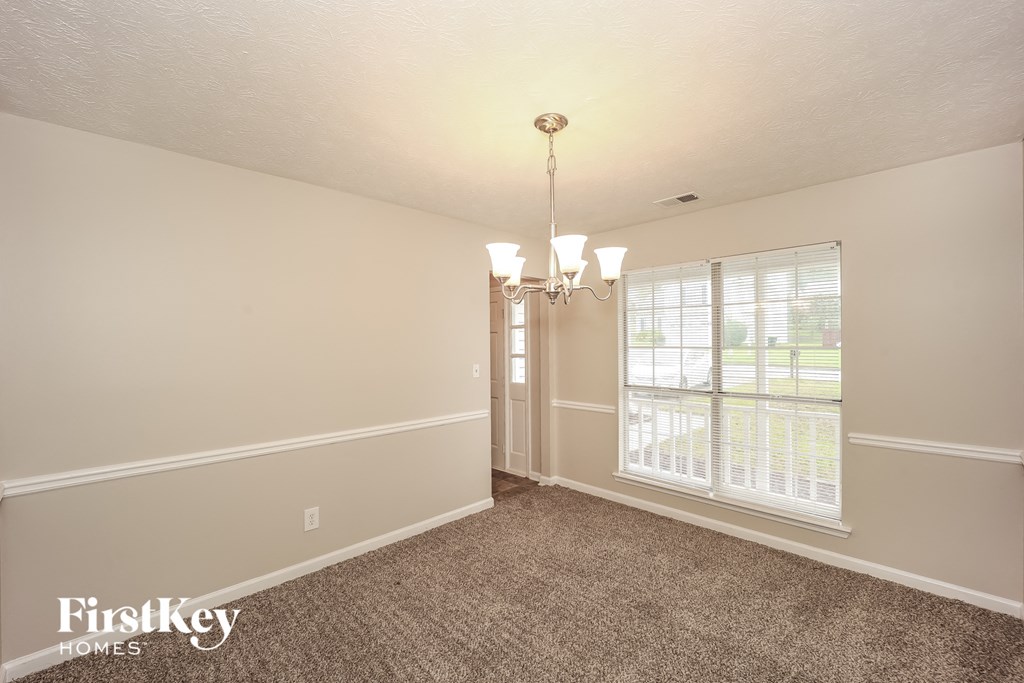an empty living room with a large window and a chandelier