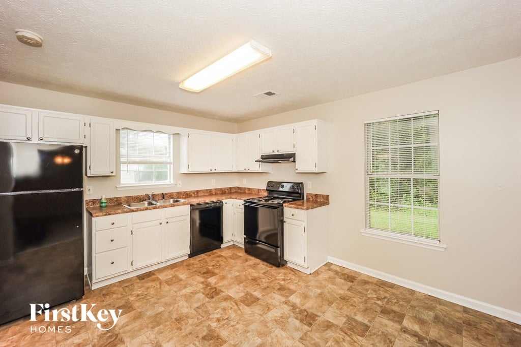 a kitchen with white cabinets and a black stove and refrigerator