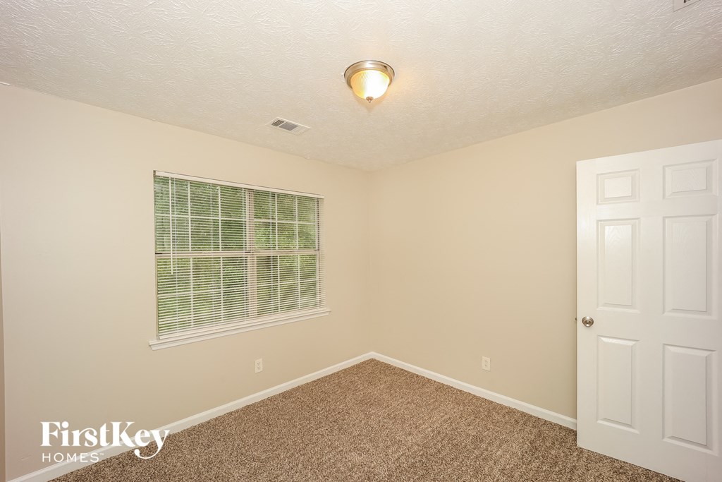 the upstairs bedroom has a large window and carpeted flooring