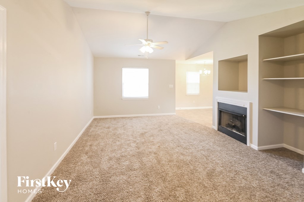 a empty living room with a fireplace and shelves
