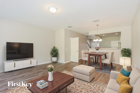 A living room with a flat screen TV, a coffee table, and a dining table with chairs.
