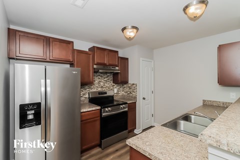 A kitchen with a refrigerator, oven, and sink.