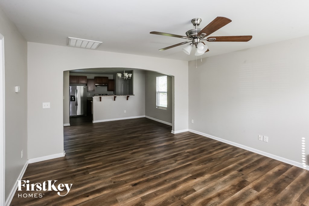 A spacious room with wooden floors and a ceiling fan.