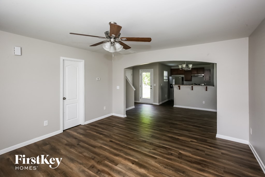 A spacious room with a ceiling fan and wooden flooring.