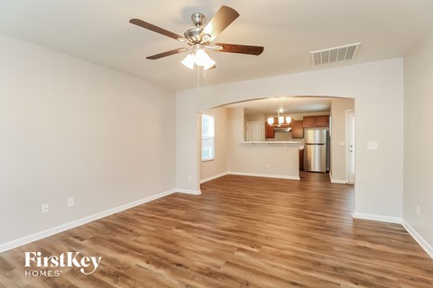 A spacious room with wooden floors and a ceiling fan.