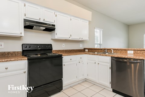 A kitchen with a black stove top oven and a stainless steel dishwasher.