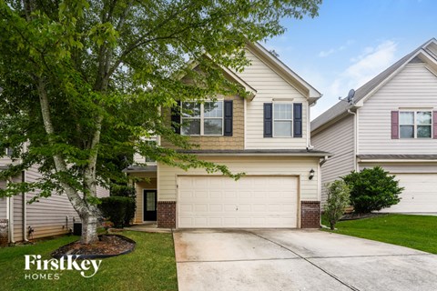A house with a garage and a tree in front of it.