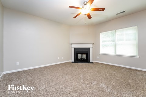 A spacious room with a fireplace and a ceiling fan.