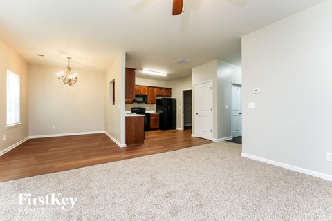 A spacious living room with a kitchen in the background.