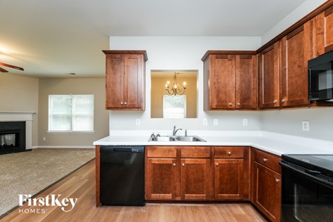 A kitchen with wooden cabinets and a black dishwasher.