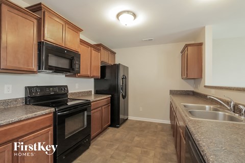 A kitchen with brown cabinets and black appliances.