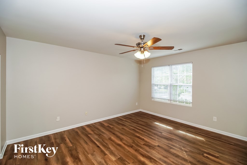 A room with a ceiling fan and wooden flooring.