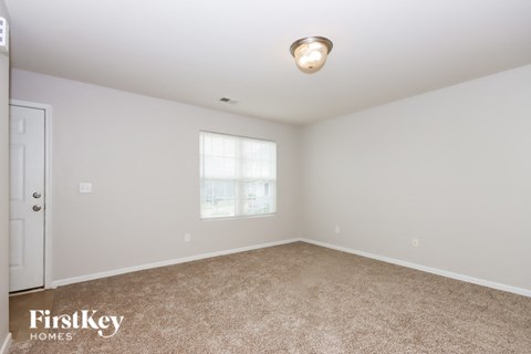 A spacious room with a carpeted floor and a window letting in natural light.