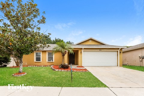 a yellow house with a palm tree in the front yard