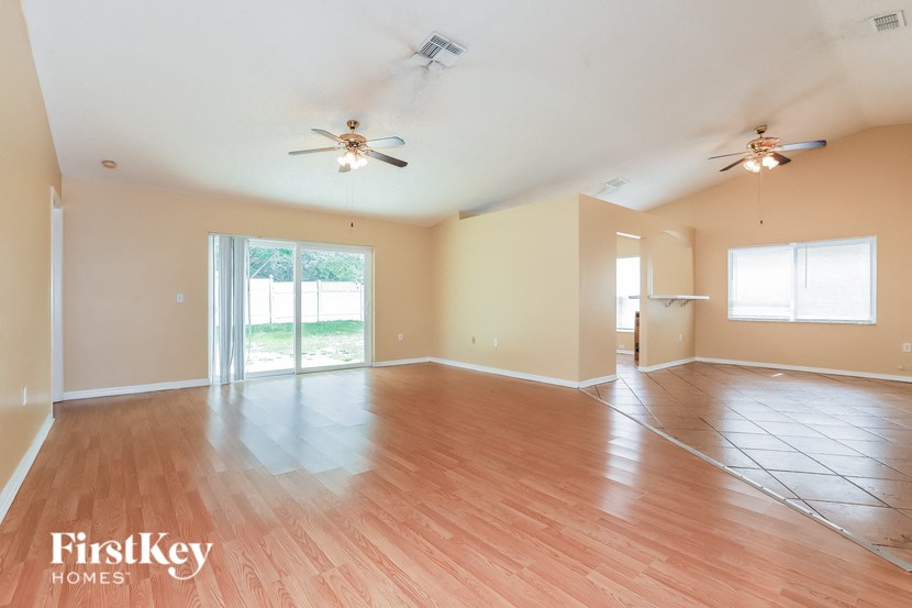 an empty living room with wood flooring and ceiling fans