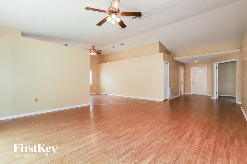 a empty living room with a ceiling fan and wood floors