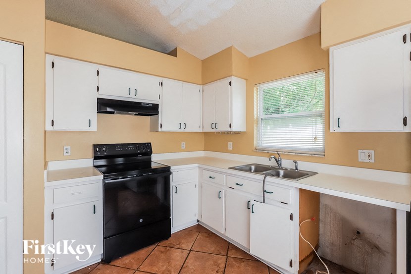 a kitchen with white cabinets and black appliances