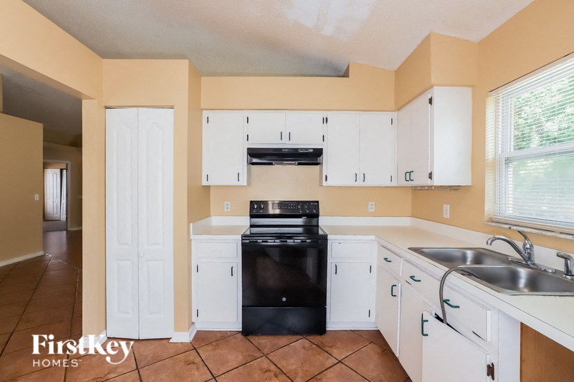 a kitchen with white cabinets and a black stove
