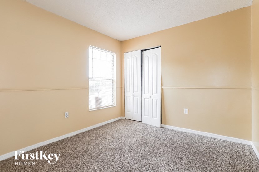 a room with carpet and two doors and a window