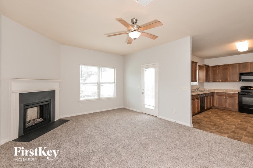 an empty living room with a fireplace and a kitchen