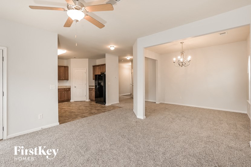 an empty living room with a ceiling fan and a kitchen