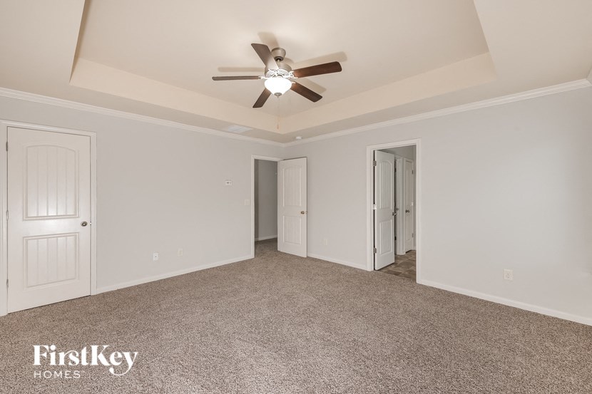 a bedroom with white walls and a ceiling fan