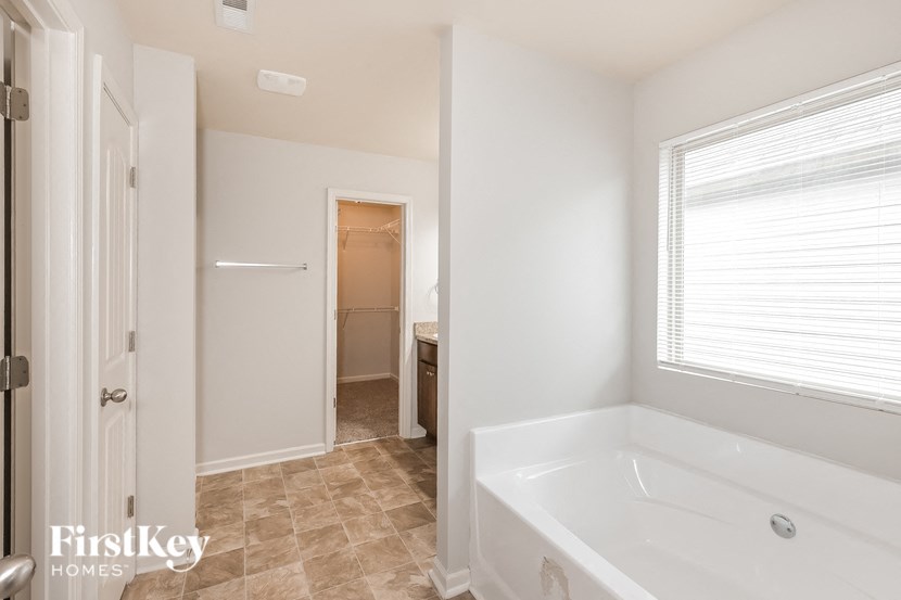 a white bathroom with a large tub and a window