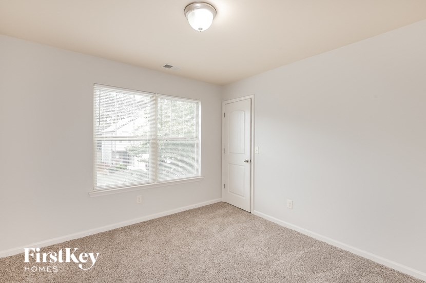 a bedroom with a door and a window and a carpeted floor