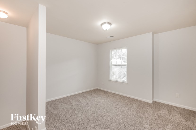 a bedroom with white walls and carpet and a window