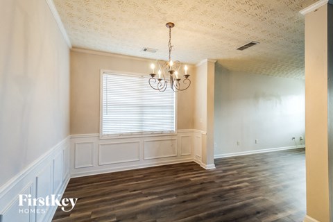 an empty dining room with wood floors and a chandelier