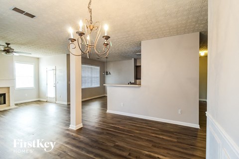 an empty living room and kitchen with wood floors and a chandelier