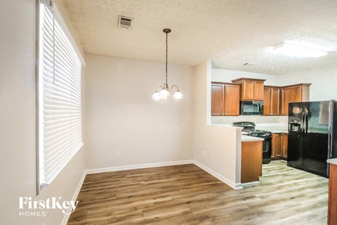 a kitchen and living room with wood flooring and a black refrigerator