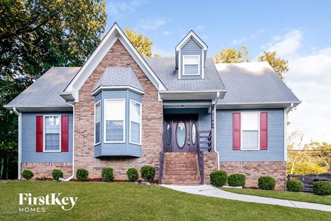 a blue house with blue and red shutters and a lawn