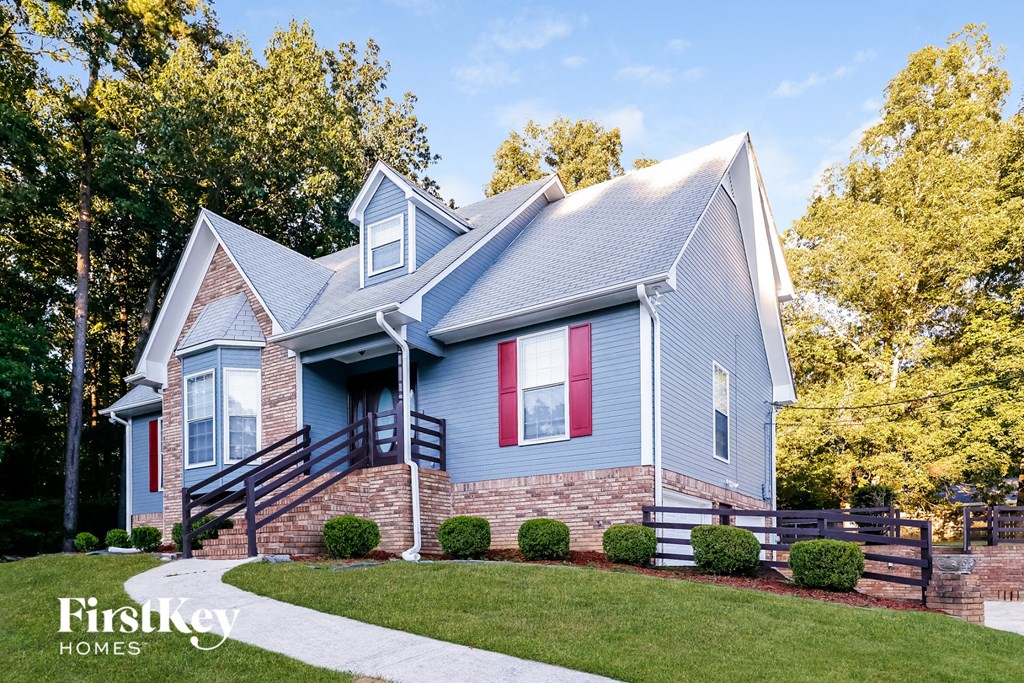 a blue house with red shutters and a brick sidewalk
