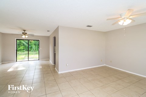 A spacious room with a sliding glass door leading to a green outdoor area.