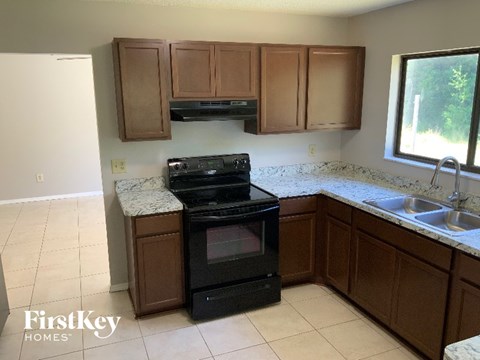A kitchen with a black stove top oven and wooden cabinets.