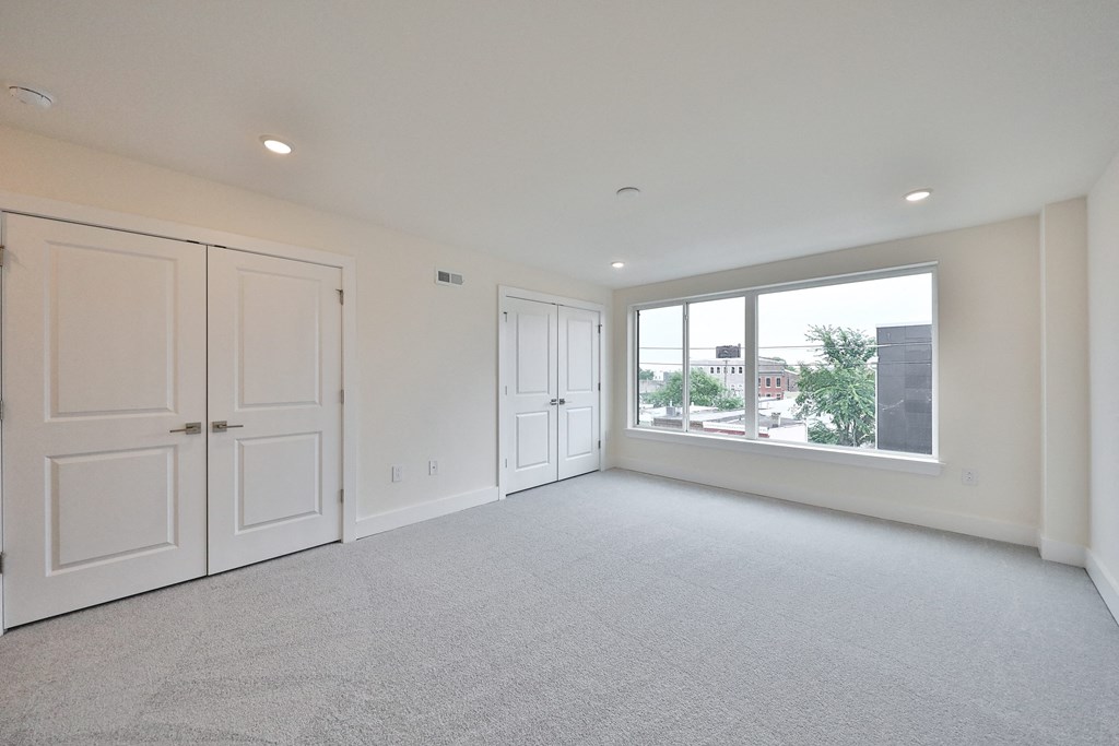 an empty living room with white walls and a large window