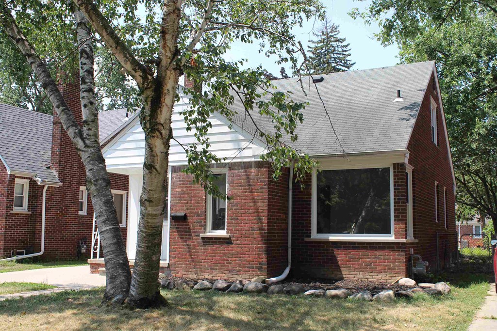 a red brick house with a tree in front of it