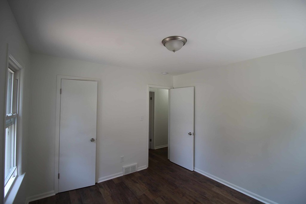 a room with white walls and a wooden floor and two doors